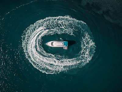 jet ski wake surrounding yacht from above 